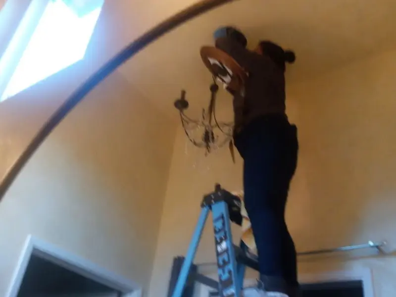 Electrician installing a chandelier in a Milaca residence